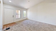 Located at 1701 N Jones Blvd in Las Vegas, NV, this two-bedroom, one-bathroom unit offers a well-organized single-level floor plan designed for comfortable everyday living. The combined kitchen and living room serves as the heart of the home, featuring vaulted ceilings with a ceiling fan, a skylight that draws in natural light, and warm wood-look flooring. The kitchen is equipped with oak-toned cabinetry offering ample storage, white appliances including a gas range, dishwasher, and refrigerator, along with a double sink and light countertops. The living area flows seamlessly from the kitchen and features plush carpeting, a front entry door, and windows that provide views of the surrounding landscape. Both bedrooms are carpeted and filled with natural light courtesy of large windows — the primary bedroom benefits from dual windows offering pleasant outdoor views, while the secondary bedroom is a quiet, versatile space. A connecting hallway leads to the full bathroom, which features a tub and shower combination with a curtain rod, a wood-vanity with overhead cabinetry, wood-look flooring, and clean white walls. The overall aesthetic is bright and neutral throughout, creating a move-in-ready canvas.