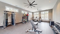 Located at 44000 Owl Wood Lane in Summerville, SC, this dedicated fitness center offers a generously sized, single-floor exercise room designed to support a comprehensive workout experience. The space is bathed in natural light, courtesy of large windows along multiple walls, as well as clerestory windows positioned near the roofline that draw in additional daylight without compromising wall space for equipment.

The room features durable, low-maintenance flooring throughout and is climate-controlled by two large-blade ceiling fans that ensure consistent airflow across the entire area. Recessed lighting complements the natural illumination for evening or overcast-day use.

Equipment is thoughtfully arranged to maximize open floor space and ease of movement. Cardio offerings include multiple treadmills, a stationary bike, an elliptical trainer, and a rowing machine. Strength training is well-represented with a Matrix functional trainer cable machine, a full rack of dumbbells, a weight bench, and a versatile functional training rig stocked with kettlebells, medicine balls, resistance tools, and a heavy bag. A wall-mounted television, open storage shelving, and a bench near the entry provide added convenience. The neutral gray tones of the walls and flooring create a clean, focused atmosphere conducive to fitness.