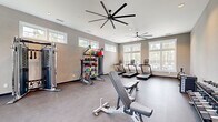 Located at 44000 Owl Wood Lane in Summerville, SC, this dedicated fitness center offers a generously sized, single-floor exercise room designed to support a comprehensive workout experience. The space is bathed in natural light, courtesy of large windows along multiple walls, as well as clerestory windows positioned near the roofline that draw in additional daylight without compromising wall space for equipment.

The room features durable, low-maintenance flooring throughout and is climate-controlled by two large-blade ceiling fans that ensure consistent airflow across the entire area. Recessed lighting complements the natural illumination for evening or overcast-day use.

Equipment is thoughtfully arranged to maximize open floor space and ease of movement. Cardio offerings include multiple treadmills, a stationary bike, an elliptical trainer, and a rowing machine. Strength training is well-represented with a Matrix functional trainer cable machine, a full rack of dumbbells, a weight bench, and a versatile functional training rig stocked with kettlebells, medicine balls, resistance tools, and a heavy bag. A wall-mounted television, open storage shelving, and a bench near the entry provide added convenience. The neutral gray tones of the walls and flooring create a clean, focused atmosphere conducive to fitness.