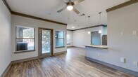Located at 4651 S Custer Rd in McKinney, TX, this well-appointed one-bedroom, one-bathroom unit offers a thoughtfully designed single-floor layout. The open-concept living, dining, and kitchen area serves as the heart of the home, featuring wood-style flooring, crown molding, and a ceiling fan that enhances the bright, airy atmosphere. Multiple windows invite natural light throughout the main living space, which also provides direct access to a private patio.

The kitchen is equipped with stainless steel appliances — including a refrigerator, range, and microwave — complemented by rich dark cabinetry, granite countertops, a subway tile backsplash, and a peninsula with pendant lighting that doubles as a dining area. A pantry and dedicated utility room add practical storage and functionality.

The bedroom features plush carpeting, a ceiling fan, and a generous window. Three closets provide ample storage, including a walk-in closet accessible through the bathroom. The bathroom includes a soaking tub with subway tile surround and wood-style flooring. A dedicated laundry area and additional utility space round out this efficiently organized and comfortable home.