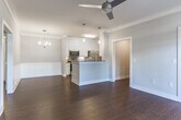 This single-floor residence in Auburn, Alabama, offers a thoughtfully designed layout with a cohesive blend of classic and contemporary finishes. Rich hardwood-style flooring runs throughout the main living areas, complemented by crisp white trim, crown molding, and neutral gray walls that create a clean, inviting atmosphere.

The open-concept living and dining area is a standout feature, offering generous space beneath ceiling fans with stylish fixtures. A wainscoted accent wall adds architectural character to the dining zone, which is illuminated by a chandelier and pendant lighting. The kitchen is efficiently laid out with tall white shaker cabinetry, a subway tile backsplash, light countertops, and a full suite of stainless steel appliances, including a range, over-the-range microwave, and French door refrigerator. A peninsula with pendant lighting connects the kitchen to the living space.

The bedroom features plush carpeting, a ceiling fan, a tray ceiling detail, and multiple windows that allow natural light to filter in through blinds. The bathroom is well-appointed with a long white vanity, framed mirror, walk-in glass shower, and matching hardwood-style flooring, offering a clean and functional design throughout.