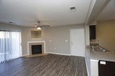 This single-floor residential unit offers a thoughtfully designed layout that balances comfort and functionality. The living area serves as the heart of the home, featuring rich hardwood-style flooring, a ceiling fan, and a tile-surround fireplace with a built-in niche above — adding both warmth and character. A sliding glass door floods the space with natural light and provides access to an outdoor area. The open-concept design connects the living space to the kitchen via a pass-through counter, creating a seamless flow ideal for everyday living and entertaining. The kitchen is well-appointed with dark espresso cabinetry, light countertops, black appliances including a refrigerator, range, and dishwasher, and continued hardwood-style flooring. Bedrooms are carpeted for comfort, each equipped with ceiling fans and ample closet space. One bedroom features a spacious walk-in closet outfitted with white wire shelving and hanging rods along two walls, offering generous storage. The bathroom includes a full tub-and-shower combination with clean white subway tile surround and chrome fixtures. Neutral gray tones throughout the unit create a cohesive, move-in ready aesthetic.