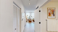 Located in Miami's vibrant Wynwood district at 2214 N Miami Ave, this thoughtfully designed single-floor unit offers a compact yet highly functional layout. The entrance hallway, flanked by louvered closet doors, leads into a bright, open-concept living and kitchen area finished with large-format light tile flooring throughout.

The kitchen is outfitted with modern cabinetry in a muted blue-grey palette, stainless steel appliances including a full-size refrigerator and built-in microwave, and a wooden island with bar seating — providing both prep space and a casual dining option. Recessed lighting and clean white ceilings enhance the airy feel.

The living area benefits from floor-to-ceiling sheer-draped windows that flood the space with natural light and offer open views of the Miami skyline. The bedroom area similarly features large windows with expansive city views, creating a bright and connected atmosphere.

The bathroom is well-appointed with travertine-style tile flooring, a large walk-in glass-enclosed shower finished with wood-toned wall tiles, matte black fixtures, and a frameless glass door — delivering a spa-like aesthetic. Curated artwork and warm, neutral tones throughout the space contribute to a cohesive and sophisticated design sensibility.