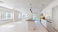 Located at 2 Rivers Run Dr. in Schenectady, NY, this thoughtfully designed 2-bedroom, 3-bathroom single-floor residence offers a bright, modern living experience with a clean, neutral aesthetic throughout. A welcoming hallway with light hardwood-style flooring leads into the open-concept living, dining, and kitchen area — the heart of the home. The kitchen is well-appointed with white shaker cabinetry, granite countertops, a classic subway tile backsplash, stainless steel appliances, and a central island with pendant lighting. The spacious living area is bathed in natural light from multiple windows and a sliding glass door that opens to a balcony with outdoor views. Both bedrooms feature plush carpeting and generous windows overlooking the surrounding landscape. The sizable primary bedroom includes its own dedicated bathroom with an extended white vanity, ample cabinetry, and light tile flooring. A second full bathroom mirrors the same clean, contemporary design, and a third bathroom provides added convenience. Four closets offer excellent storage throughout. A dedicated laundry room houses a full-size washer and dryer. The home's consistent use of crisp white tones, recessed lighting, and modern fixtures creates a cohesive, move-in-ready environment.