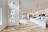 Located at 2611 First St in Napa, CA, this contemporary single-story home offers 3 bedrooms, 2 bathrooms, and a thoughtfully designed open-concept layout. The living, dining, and kitchen areas flow seamlessly together beneath soaring ceilings that amplify the sense of space and light. Tall clerestory windows and sliding glass doors flood the interior with natural light, while light-toned hardwood-style flooring runs throughout the main living areas, creating a clean, cohesive aesthetic. The kitchen is a standout feature, showcasing a large center island with a quartz countertop, two-tone cabinetry with dark lower cabinets and crisp white uppers, a striking marble-style backsplash, and stainless steel appliances including a refrigerator, range, microwave, and dishwasher. Pendant lighting adds warmth above the island. The bedrooms are carpeted for comfort, with the primary bedroom offering generous proportions and a wall-mounted mini-split system. Secondary bedrooms feature large windows that frame outdoor views. The bathrooms are finished in a modern style with dark wood vanities, white countertops, and glass-enclosed shower-tub combinations. Five closets and a dedicated laundry room provide ample storage throughout this well-appointed Napa home.