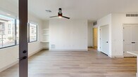 Located at 4900 East Deer Valley Drive in Phoenix, AZ, this modern one-bedroom, one-bathroom residence offers a thoughtfully designed single-floor layout with clean, contemporary finishes throughout. The open-concept kitchen and living area serves as the heart of the home, anchored by a large white quartz island with a black matte sink and dual pendant lights overhead. The kitchen features flat-front cabinetry in a warm greige tone, a crisp white subway tile backsplash, white quartz countertops, and a full suite of stainless steel appliances including a refrigerator, range, and microwave. Light wood-look flooring runs throughout the main living areas, complementing the bright, neutral palette. The living room offers built-in shelving, a ceiling fan with integrated lighting, and a glass door leading to an outdoor area, allowing natural light to fill the space. The bedroom is carpeted for comfort, includes a ceiling fan, and features a large window with views of the surrounding neighborhood. The bathroom is finished with marble-style tile surrounds in the tub/shower combination, matte black fixtures, and a vanity with quartz countertops, maintaining the cohesive modern aesthetic found throughout the home.