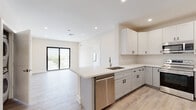 Located at 3728 SW 12th Pl in Fort Lauderdale, FL, this thoughtfully designed single-floor residence combines modern finishes with a bright, open layout. The heart of the home is a contemporary open-concept kitchen featuring shaker-style white cabinetry with black hardware, light quartz countertops, a peninsula with an undermount sink, and a full suite of stainless steel appliances including a range, over-the-range microwave, dishwasher, and refrigerator. Light wood-look flooring flows throughout the entire unit, enhancing the clean, cohesive aesthetic. The living area is generously proportioned, bathed in natural light, and opens directly onto a private balcony through sleek black-framed sliding glass doors, offering pleasant outdoor views. Bedrooms are well-sized, each featuring ceiling fans, black-framed windows with roller shades, and access to ample closet space, including a walk-in closet with built-in shelving. The bathrooms are elegantly finished with large-format marble-look tile, a soaking tub with brushed gold fixtures, and a wide gray vanity topped with a white quartz surface. Recessed lighting throughout and a neutral color palette give the entire space a fresh, move-in-ready appeal.