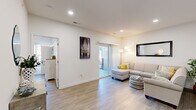 This thoughtfully designed one-bedroom, one-bathroom unit offers an efficient and functional layout across a single floor. The open-concept living area seamlessly connects the kitchen, dining, and living spaces, creating a bright and airy atmosphere enhanced by recessed lighting and light-toned luxury vinyl plank flooring throughout.

The kitchen is a standout feature, anchored by a large central island with granite countertops, an undermount sink, and pendant lighting overhead. Grey shaker-style cabinetry lines the walls, complemented by stainless steel appliances including a refrigerator, range, and microwave. The adjacent dining area comfortably accommodates a round table and chairs, while the living room offers generous space and direct access to a private balcony through sliding glass doors.

The bedroom is a comfortable retreat, featuring a ceiling fan, a window with natural light, and direct access to the bathroom. The bathroom includes a glass-enclosed shower and vanity with grey cabinetry, consistent with the home's cohesive design palette.

A dedicated laundry room with a full-size washer and dryer adds everyday convenience. Throughout, the space maintains a clean, modern aesthetic with white walls, neutral finishes, and an efficient floor plan that maximizes every square foot.