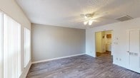 Located at 620 N Litchfield Rd in Goodyear, Arizona, this single-story home offers a well-organized layout with a variety of functional living spaces. The main living areas feature wood-look plank flooring and textured ceilings, lending the space a clean, contemporary feel. Ceiling fans with light fixtures are present throughout, ensuring comfort year-round in Arizona's warm climate.

The living room is bright and open, with large windows allowing natural light to fill the space, and a front entry door provides direct outdoor access. It connects seamlessly to a second living or dining area, which flows directly into the kitchen. The kitchen is equipped with warm wood-toned cabinetry, a gas range, built-in microwave, refrigerator, and ample counter space. An adjacent laundry area accommodates a full-size washer and dryer.

The bedrooms are carpeted for comfort and feature multiple windows with vertical blinds, offering adjustable natural light. One bedroom includes sliding glass doors that open to an outdoor patio area. The bathrooms include a tub-shower combination with tiled surrounds accented by a decorative mosaic border, wood-look flooring, and clean white fixtures. The hallway connecting the bedrooms and bathrooms provides convenient access throughout the home.