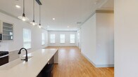 Located in Huntsville, AL, this single-floor space showcases a clean, modern design with an open-concept layout that seamlessly connects the main living areas. Light hardwood flooring runs throughout, complementing the crisp white walls and creating a bright, airy atmosphere.

The kitchen is a standout feature, centered around a bold two-tone island with a white quartz countertop and dark base, illuminated by a trio of matte black pendant lights. Gray shaker-style cabinetry lines the walls, paired with a subway tile backsplash and a full suite of stainless steel appliances, including a French door refrigerator, gas range, and built-in microwave.

The open living and dining area is bathed in natural light through a row of windows fitted with white blinds, and recessed lighting provides even illumination throughout. A separate bedroom offers additional windows, a ceiling fan, and continued hardwood flooring, providing a comfortable and well-lit retreat.

The bathroom features a frameless sliding glass shower enclosure with large-format tile surround and polished chrome hardware, lending a refined, contemporary finish. The single-story floor plan is efficient and well-organized, making this a thoughtfully designed space in the heart of Huntsville.