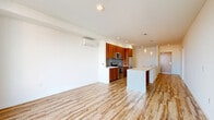 Located at 1255 Harrison Street in Seattle's South Lake Union neighborhood, this well-appointed one-bedroom, one-bathroom residence offers a thoughtfully designed open-concept layout with modern finishes throughout. Light hardwood flooring flows seamlessly across the entire unit, complementing the clean, contemporary aesthetic.

The combined living, dining, and kitchen area serves as the heart of the home. The kitchen is outfitted with rich wood cabinetry, stainless steel appliances including a range, microwave, and refrigerator, and an expansive white quartz waterfall island with an integrated sink — ideal for both meal preparation and casual dining. Pendant lighting above the island adds a stylish touch, while a wall-mounted mini-split unit provides efficient climate control.

Floor-to-ceiling windows in the living area and bedroom flood the space with natural light and frame urban views of the Seattle skyline. The bedroom is generously proportioned and connects to a well-organized walk-in closet featuring built-in shelving and hanging rods.

The full bathroom showcases a floating wood vanity with a white countertop, a large mirror, and a tiled soaking tub and shower combination. A dedicated in-unit laundry space accommodates a full-sized stacked washer and dryer. The unit also includes a separate closet for additional storage.