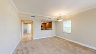 Located at Emerson Plaza in Altamonte Springs, FL, this well-appointed one-bedroom, one-bathroom residence offers a thoughtfully designed single-level layout with nearly 1,000 square feet of living space. The open-concept living room is generously sized, featuring warm neutral tones, soft carpet flooring, crown molding, and a ceiling fan with pendant lighting. An arched pass-through connects the living area to the kitchen, which is outfitted with rich wood cabinetry, granite countertops, tile flooring, and stainless steel appliances including a refrigerator, range, and dishwasher. The spacious primary bedroom comfortably accommodates large furnishings and includes carpet flooring, crown molding, a ceiling fan, and a window offering pleasant outdoor views. The full bathroom is bright and functional, featuring tile flooring, a vanity with ample cabinetry, a walk-in glass shower with tile surround, and a window that brings in natural light. Additional highlights include a dedicated laundry room with washer/dryer connections, a closet for extra storage, and a hallway that connects the rooms efficiently. The warm, neutral color palette throughout creates a cohesive and inviting atmosphere.