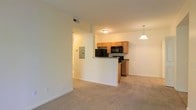 Located at 471 N Hamilton Rd in Gahanna, Ohio, this single-floor unit offers a practical and open layout designed for comfortable everyday living. The living area features neutral-toned carpeting that extends throughout the space, creating a cohesive and understated aesthetic.

The kitchen is positioned adjacent to the living area and is partially separated by a half-wall peninsula, which provides both a visual boundary and additional counter space. Warm honey-toned wood cabinetry lines the kitchen walls, complemented by dark granite-style countertops and black appliances, including a refrigerator, microwave, and range. A pendant light hangs above the peninsula, adding a focused point of illumination to the kitchen area.

The living space is bright and open, with light-colored walls that reflect the overhead lighting effectively. A hallway visible from the main living area provides access to additional rooms within the unit. An electrical panel is conveniently accessible along the hallway wall. The overall ambiance is clean and functional, with a neutral palette that offers flexibility for a variety of interior styles.