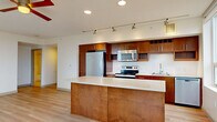 Located at 1000 Minor Ave in Seattle's First Hill neighborhood, this 3-bedroom, 2-bathroom unit offers a well-designed single-floor layout that maximizes functionality throughout. The open-concept kitchen and living area serves as the heart of the home, featuring warm wood cabinetry, a classic white subway tile backsplash, stainless steel appliances including a refrigerator, range, and built-in microwave, and a generous island with a light stone countertop — ideal for both cooking and casual dining. Track lighting overhead and light-toned hardwood flooring carry throughout the main living areas, creating a bright and cohesive aesthetic. The bedrooms are comfortably sized, with the primary bedroom offering a walk-in closet with built-in shelving and hanging rods. Additional bedrooms include sliding-door closets with built-in organizers and large windows that frame urban Seattle views, filling each room with natural light. The bathrooms are finished with light tile flooring, warm wood vanities with framed mirrors, and clean, understated fixtures. A hallway connects the private and shared spaces efficiently, with a dedicated closet providing additional storage. The overall design balances modern finishes with a clean, neutral palette throughout.