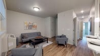 This single-floor residence at 20945 NW Quatama Rd in Beaverton, Oregon offers a thoughtfully designed layout that balances functionality and comfort. The living room serves as the heart of the space, featuring wood-style flooring, neutral walls, and a textured ceiling. A window overlooking lush greenery draws in natural light and provides pleasant outdoor views, while a wall-mounted HVAC unit ensures year-round climate control.

Adjacent to the living area, a dedicated dining nook is illuminated by a modern chandelier and benefits from a large window that further brightens the space with natural light. The galley-style kitchen is well-equipped with dark cabinetry, white quartz countertops, a classic subway tile backsplash, and a full suite of stainless steel appliances, including a refrigerator, range, microwave, and dishwasher. Wood-style flooring continues throughout, creating a cohesive feel.

The bedroom is a quiet retreat with carpeted flooring and a window fitted with blinds. Two bathrooms serve the unit: a full bath with a tub-shower combination, wood-look flooring, and open shelving, and a second bath featuring a vanity with storage and wood-style flooring. The overall aesthetic is clean, modern, and move-in ready.