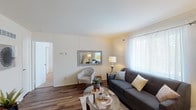 Located at 6977 Bluewater Trl in Marlborough, Missouri, this single-floor residence offers a thoughtfully designed layout with a warm and inviting ambiance throughout. Rich hardwood-style flooring flows through the main living areas, creating a cohesive and polished aesthetic.

The living room is a comfortable, well-lit space featuring a large window dressed with sheer curtains that allow natural light to fill the room. A decorative mirror on the wall adds depth and brightness to the area.

Adjacent to the living room, the dining area is highlighted by a striking full-height exposed brick accent wall that brings rustic character and texture to the space, creating a memorable focal point.

The kitchen features classic cabinetry, a gas range, white tile backsplash, and ample counter space — offering a functional and efficient cooking environment.

The bedroom is a serene retreat with plush carpeting, natural light from a window with sheer curtains, and a sliding-door closet providing generous storage.

The bathroom is cleanly finished with tile surround, a tub-shower combination, a vanity with stone-look countertop, and white wall tiles that contribute to a fresh, tidy feel.

Overall, the space balances practicality with character, making it a comfortable and distinctive home in the Marlborough community.