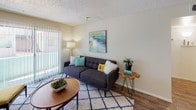 Located at 6131 N 27th Ave in Phoenix, Arizona, this single-floor residence offers a practical and comfortable layout with cohesive design details throughout. The living area provides a welcoming atmosphere, featuring wood-look flooring, a textured ceiling, and a large sliding glass door fitted with vertical blinds that allow natural light to fill the space. The galley-style kitchen is efficiently designed with warm wood cabinetry, white countertops, and black and stainless steel appliances, including a range, refrigerator, and dishwasher. The kitchen opens toward a dining area, creating a connected and functional flow between spaces. The primary bedroom is generously proportioned, offering direct access to a walk-in closet and an en-suite bathroom. The bathroom features an extended vanity with warm wood cabinetry, white countertops, and ample storage. A second bedroom provides additional flexibility, with wood-look flooring, a large window for natural light, and wall-mounted TV capability. Throughout the unit, the design maintains a consistent palette of neutral tones, warm wood finishes, and white surfaces, contributing to a clean and modern aesthetic. The overall layout is thoughtfully arranged to maximize usability within a single level.