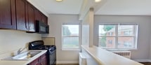 Located at 210 Wood Ridge St, Apt B, Wood-Ridge, NJ 07075, this 1-bedroom, 1-bathroom apartment spans 530 square feet across a single floor, offering an efficient and comfortable layout. The living room is the centerpiece of the unit, featuring warm hardwood floors, soft gray walls, clean white baseboards, and a large window that fills the space with natural light and views of surrounding greenery. An open pass-through connects the living area to the kitchen, which is equipped with dark cabinetry, a gas range, microwave, and refrigerator. The 150-square-foot bedroom continues the hardwood flooring and gray color palette, with a window providing natural light and outdoor views, a wall-mounted mini-split A/C unit for climate control, and a radiator for heating. A connecting hallway provides access to the full bathroom, which features light ceramic tile flooring, a white soaking tub with shower, toilet, and a window overlooking greenery. Throughout the apartment, consistent hardwood floors, neutral gray walls, and white trim create a cohesive, clean aesthetic. The unit includes both radiator heating and a ductless mini-split system for year-round comfort.