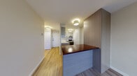 Located at 3655 Avenue Papineau in Montréal's vibrant Plateau-Mont-Royal area, this single-floor unit offers a thoughtfully designed layout with a clean, contemporary aesthetic throughout. Light-toned hardwood flooring runs continuously across the living spaces, lending a warm and cohesive feel to the interior.

The open-concept kitchen is a functional centerpiece, featuring two-tone cabinetry — white upper cabinets paired with natural wood-finish lower units — along with white countertops, a stainless steel range and refrigerator, and a peninsula topped with a rich, dark wood surface that doubles as a breakfast bar or casual dining space. A textured tile backsplash adds visual interest, while a window allows natural light to filter in and offers views of the surrounding neighbourhood.

The bedroom is a calm and comfortable retreat, featuring a built-in closet with panelled doors and direct access to additional storage. Large sliding glass doors open onto a private balcony, providing sweeping views of the Montréal skyline and the tree-lined surroundings — a standout feature of this unit.

The bathroom is finished in a crisp, all-white palette with subway tile surrounding the bathtub and shower combination, complemented by a clean vanity with an integrated sink and a frameless mirror. The entry foyer provides a practical transition into the living space, completing this well-appointed urban residence.