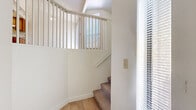 Located in Mesa, Arizona, this two-story, 2-bedroom, 2-bathroom home offers a well-organized layout with the majority of living space on the upper level. Light-toned hardwood-style flooring runs throughout, contributing to a clean, cohesive aesthetic. The open-concept main living area is anchored by a striking corner fireplace with tile surround and soaring vaulted ceilings, with sliding glass doors that invite natural light and provide access to an outdoor balcony. A decorative pendant light distinguishes the dining area, which flows seamlessly into the galley-style kitchen, featuring warm wood cabinetry, laminate countertops, and white appliances including a range and refrigerator. A dedicated laundry area includes a full-size washer and dryer with additional shelving for storage. The generously sized primary bedroom includes mirrored sliding closet doors, an en suite bathroom with a dual-sink vanity and warm wood cabinetry, and its own sliding glass door access to outdoor views. The second bedroom also benefits from natural light and convenient hallway access. A carpeted staircase with a white spindle railing connects the entry-level foyer to the main living floor, creating an inviting transition between levels. Multiple windows throughout ensure the home remains bright and airy.