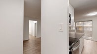 Located at 1903 Bayview Ave in Toronto's Leaside neighbourhood, this well-appointed one-bedroom, one-bathroom unit offers a thoughtfully designed layout across a single floor. Light-toned laminate flooring runs throughout the space, creating a cohesive and clean aesthetic.

The combined kitchen and living area forms the heart of the unit. The galley-style kitchen features white cabinetry, dark countertops, stainless steel appliances including a refrigerator, stove, and microwave, and a peninsula that opens toward the living space — ideal for both cooking and casual dining. The living area is bright and open, with large windows and a sliding glass door that leads to a private balcony overlooking surrounding greenery and the neighbouring brick building.

The bedroom is a comfortable, well-proportioned room with a window framing views of mature trees, a baseboard heater, and clean white walls that contribute to a calm atmosphere.

The bathroom is finished with classic white subway tile on the walls surrounding the soaker tub, complemented by a pedestal-style vanity and a window that brings in natural light and tree views.

The hallway provides a practical entry transition connecting all rooms. The private balcony adds valuable outdoor space with open views of the tree-lined surroundings.