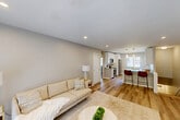 Located at 200 La Bonne Vie Drive in East Patchogue, NY, this 2-bedroom, 1-bathroom home offers a thoughtfully designed single-floor layout with a staircase entry finished in light wood flooring and clean white railings. The open-concept living and kitchen area forms the heart of the home, where light wood-tone flooring, recessed lighting, and a neutral color palette create a bright and welcoming atmosphere. The living room features a sliding glass door that opens to a private outdoor deck overlooking lush greenery, allowing for an abundance of natural light. The kitchen is outfitted with white shaker cabinetry, granite-style countertops, stainless steel appliances including a refrigerator, range, and built-in microwave, and a peninsula with bar seating—ideal for casual dining. The spacious primary bedroom includes a ceiling fan, carpeted flooring, and a window with outdoor views, while the second bedroom is cozy and well-proportioned with its own ceiling fan and ample closet access. The bathroom is finished with large-format neutral tile surrounding a full tub and shower, complemented by a marble-style vanity countertop. With four closets throughout, storage is plentiful in this comfortable and stylishly updated home.