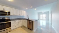 This single-floor residence offers a thoughtfully designed open layout encompassing two bedrooms and two full bathrooms. A welcoming entryway hallway with polished tile flooring leads into the main living areas, where recessed lighting and a ceiling fan complement the bright, airy atmosphere. The open-concept kitchen features white shaker-style cabinetry, granite countertops, stainless steel appliances including a refrigerator, range, microwave, and dishwasher, and a peninsula that flows seamlessly into the living area. Glass French doors in the living space invite natural light and provide access to an outdoor area with what appears to be a water view. Both bedrooms are carpeted and equipped with ceiling fans; one bedroom benefits from a window showcasing scenic water views. The two bathrooms mirror each other in finish quality, each offering white cabinetry, granite-topped vanities, and tile flooring, with one featuring a shower-tub combination. A walk-in closet is accessible from the kitchen area, adding practical storage. The overall aesthetic is clean and modern throughout.