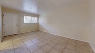 Located at 4900 Wyoming Blvd NE in Albuquerque, New Mexico, this single-floor, one-bedroom, one-bathroom unit offers a practical and well-organized layout. Light-toned tile flooring runs throughout the main living areas, reflecting natural light and creating a clean, cohesive look. The open living room provides a comfortable gathering space, while a separate dining area flows directly into the kitchen, making everyday living convenient. The galley-style kitchen is well-equipped with warm wood cabinetry, granite-style countertops, a gas range, dishwasher, refrigerator, and a double-basin sink. A window at the end of the kitchen brings in additional natural light. The bedroom features plush carpeting, a ceiling fan with light fixture, a window with outdoor views, and access to a closet. The bathroom includes a full bathtub and shower surround in a clean, white finish. A dedicated hallway connects the main living spaces, and a separate utility room adds functional storage. The unit's neutral color palette throughout creates a bright, move-in-ready atmosphere suited for comfortable daily living.