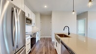 Located in the Arrowhead community of Bozeman, Montana, this well-designed one-bedroom, one-bathroom unit offers a thoughtful layout with modern finishes throughout. The open-concept living and kitchen area serves as the heart of the home, featuring durable wood-look flooring, recessed lighting, and a clean neutral color palette. The kitchen is outfitted with white shaker cabinetry, a subway tile backsplash, stainless steel appliances including a range and microwave, and a central island with a quartz countertop, undermount sink, and matte black fixtures. Stylish pendant lights hang above the island, adding a contemporary touch. A balcony off the living area provides sweeping open-field views under Montana's expansive sky. The bedroom is a bright, comfortable retreat with multiple windows fitted with roller shades, allowing natural light to fill the space while overlooking the surrounding landscape. The full bathroom features a tub-shower combination with matte black hardware, a quartz-topped vanity, and direct access to a generously sized walk-in closet complete with built-in shelving and dual hanging rods. Consistent wood-look flooring, five-panel white doors with matte black hardware, and clean wall tones unify the space with a cohesive, modern aesthetic.