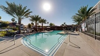 Located at 2420 Cardinal Drive in San Diego, California, this outdoor amenity space showcases a well-appointed, resort-style pool area designed for relaxation and recreation. The centerpiece is a generously sized swimming pool with clear, blue-green water, framed by a clean concrete pool deck that provides ample space for lounging. A separate spa is conveniently situated adjacent to the main pool, offering a dedicated space for relaxation. Tall, mature palm trees are thoughtfully distributed throughout the area, providing natural shade and reinforcing the Southern California aesthetic. A covered pavilion anchors one end of the space, featuring an outdoor dining and seating area ideal for social gatherings, shielded from the sun by a modern pergola-style roof structure. Additional lounge chairs are arranged along the pool deck, offering multiple spots to enjoy the abundant natural sunlight. The perimeter of the pool area is enclosed by a contemporary black metal fence, providing both security and a clean visual border. Manicured landscaping with drought-tolerant plantings lines the walkways and building perimeters, adding color and texture to the hardscape. The multi-story residential building overlooking the pool area features balconies that offer elevated views of this vibrant outdoor space.