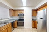 Located in the heart of Washington, DC's West End neighborhood, this one-bedroom residence offers a thoughtfully designed layout across a single floor. The kitchen is well-appointed with warm honey-toned cabinetry, granite-look countertops, stainless steel appliances including a range, microwave, dishwasher, and refrigerator, and light tile flooring. A peninsula with an integrated sink opens the kitchen toward the living area, which features hardwood-style flooring and a large window that fills the space with natural light. The generously sized bedroom is carpeted and bathed in natural light from a wide, multi-pane window overlooking the surrounding urban streetscape. A hallway connects the main living spaces and provides access to a full bathroom finished with classic white tile. The unit also includes a mirrored closet offering ample storage. Textured ceilings and clean white walls are consistent throughout, contributing to a neutral, move-in-ready aesthetic. The efficient floor plan makes excellent use of the available space, providing comfortable living in one of DC's most walkable and well-connected neighborhoods.