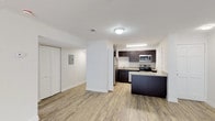 This single-floor residence offers three bedrooms and two bathrooms within a well-organized layout. Light wood-style flooring extends throughout the main living areas and bedrooms, complementing the bright, neutral color palette that defines the interior. The open-concept design connects the living area to the kitchen, creating a cohesive and functional shared space. A large sliding glass door in the living area allows natural light to fill the room, contributing to an airy atmosphere.

The kitchen is equipped with dark espresso cabinetry, granite-patterned countertops, and a full suite of stainless steel appliances, including a refrigerator, range, microwave, and dishwasher. A peninsula with matching countertop provides additional workspace and casual seating potential, while serving as a natural divider between the kitchen and living space.

The bedrooms are generously proportioned, with neutral walls and windows that invite natural light. Both bathrooms feature tub-shower combinations with large-format tile surrounds in a warm beige tone, white vanities, and brushed nickel fixtures, offering a clean and consistent aesthetic. Textured ceilings are present throughout, and ample closet storage is provided across the unit.
