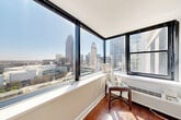 Located in the heart of Midtown Atlanta, this one-bedroom, one-bathroom residence at 1270 W Peachtree St NW offers a well-designed layout with a seamless blend of comfort and urban sophistication. Rich hardwood flooring runs throughout the main living areas, complemented by crown molding and neutral gray walls that create a clean, contemporary aesthetic.

The combined kitchen and living area serves as the central hub of the home. The kitchen is outfitted with white shaker cabinetry, dark granite countertops, a white subway tile backsplash, and a full suite of stainless steel appliances including a dishwasher, range, and refrigerator. The open living room connects to a glass-enclosed sunroom-style nook featuring floor-to-ceiling wraparound windows that showcase breathtaking panoramic views of the Atlanta skyline — a true standout feature of this residence.

The bedroom is a calm retreat with plush carpeting, crown molding, and a window allowing natural light and city views. The full bathroom includes a tiled tub-shower combination with warm neutral tile, a vanity, and hardwood-style flooring. An entrance foyer provides a welcoming transition into the home. Every room benefits from abundant natural light, making this Midtown location an exceptional urban living opportunity.