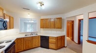 This single-floor home offers a practical and comfortable layout designed for everyday living. The kitchen is well-equipped with warm oak cabinetry, light countertops, a double stainless steel sink, and a full suite of appliances including a refrigerator, electric range, built-in microwave, and dishwasher. Light tile flooring and a window overlooking the outdoors give the kitchen a bright, functional character.

The living area is generously proportioned, featuring plush carpeting, a fireplace, and large windows that invite abundant natural light, creating a welcoming and open atmosphere. The floor plan, as seen from the overhead view, reveals a thoughtfully arranged layout with clear transitions between living, dining, and private spaces.

The bedrooms are comfortably sized, each featuring soft wall-to-wall carpeting, neutral tones, and windows that allow natural light to filter in. One bedroom includes a built-in closet with sliding doors for organized storage.

The bathrooms are finished consistently throughout, featuring warm oak vanity cabinetry, light tile flooring, matching wall-mounted oak storage cabinets, and chrome fixtures and towel bars. Warm wood trim and baseboards carry through each room, tying the home's design together with a cohesive, classic aesthetic.