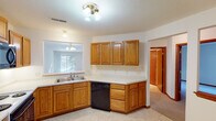 This single-floor home offers a practical and comfortable layout designed for everyday living. The kitchen is well-equipped with warm oak cabinetry, light countertops, a double stainless steel sink, and a full suite of appliances including a refrigerator, electric range, built-in microwave, and dishwasher. Light tile flooring and a window overlooking the outdoors give the kitchen a bright, functional character.

The living area is generously proportioned, featuring plush carpeting, a fireplace, and large windows that invite abundant natural light, creating a welcoming and open atmosphere. The floor plan, as seen from the overhead view, reveals a thoughtfully arranged layout with clear transitions between living, dining, and private spaces.

The bedrooms are comfortably sized, each featuring soft wall-to-wall carpeting, neutral tones, and windows that allow natural light to filter in. One bedroom includes a built-in closet with sliding doors for organized storage.

The bathrooms are finished consistently throughout, featuring warm oak vanity cabinetry, light tile flooring, matching wall-mounted oak storage cabinets, and chrome fixtures and towel bars. Warm wood trim and baseboards carry through each room, tying the home's design together with a cohesive, classic aesthetic.