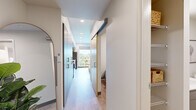 Located at 1411 E Iron Bridge Way in Spokane, WA, this well-designed one-bedroom, one-bathroom unit offers a smart, functional layout across a single floor. Light wood-style flooring runs throughout, lending a clean, cohesive aesthetic to the entire space.

The kitchen and living area form an open, combined zone anchored by a thoughtfully appointed kitchen. Bold navy upper cabinetry contrasts with lighter lower cabinets and bright white countertops, creating a striking two-tone design. Stainless steel appliances — including a refrigerator, range, microwave, and dishwasher — complete the fully equipped setup. A large window at the end of the kitchen/living space frames lush outdoor greenery, flooding the area with natural light.

The living room accommodates comfortable seating and benefits from a wall-mounted mini-split HVAC unit, providing efficient climate control year-round. A sliding barn-style door adds a modern architectural touch to the hallway leading to the private spaces.

The bedroom is a cozy, neutral-toned retreat with warm lighting and clean walls. The bathroom is efficiently designed, featuring a gray vanity with white countertop and, notably, an in-unit stacked washer and dryer — a highly practical inclusion. The hallway also features built-in storage and organizational systems, maximizing every inch of available space.