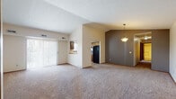 Located at 1426 Clearbrooke Dr in Brunswick, Ohio, this single-floor residence offers a practical and comfortable layout with a variety of functional living spaces. The open living and dining area is a standout feature, highlighted by soaring vaulted ceilings that create an airy, expansive feel. Plush wall-to-wall carpeting runs throughout the main living areas, while a pendant light fixture adds a touch of warmth to the dining space. A sliding glass door with vertical blinds allows natural light to flow in and provides access to the outdoors. The kitchen is positioned adjacent to the living area, connected via a convenient pass-through window. It features dark wood cabinetry, light countertops, a double sink, a dishwasher, and durable wood-look flooring, with a window above the sink bringing in additional natural light. The bedrooms are carpeted and well-proportioned, each offering windows for natural light and closet storage with wood-paneled doors. The bathroom is clean and functional, equipped with a tub-shower combination, a vanity with storage, and wood-look flooring that complements the kitchen. Throughout the home, neutral tones and consistent finishes create a cohesive and inviting atmosphere.