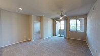This single-story residence offers a thoughtfully designed layout with a range of functional spaces throughout. The open living area is generously proportioned, featuring neutral-toned carpet, a ceiling fan, and sliding glass doors that lead to a private balcony, allowing natural light to fill the room. An additional window with blinds further brightens the space.

The kitchen is well-appointed with dark espresso cabinetry, granite-style countertops, a central island with a double stainless steel sink, pendant lighting, track lighting, and a full suite of stainless steel appliances including a refrigerator, range, and built-in microwave. Directly accessible from the kitchen is a dedicated laundry room housing a full-size washer and dryer.

Multiple bedrooms feature plush carpeting, ceiling fans, and windows with blinds providing natural light and privacy. One carpeted bedroom includes a narrow vertical window, while another offers dual windows and a ceiling fan.

Two bathrooms serve the residence. One features a tub-shower combination, wood-look flooring, and a dark vanity with white countertop. The other offers a dual-sink vanity with navy cabinetry, a walk-in shower with glass enclosure, and a built-in medicine cabinet with shelving.