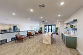 Located at 4005 State Farm Pkwy in Columbia, Missouri, this thoughtfully designed upper-floor communal space spans a generous footprint and offers a polished, contemporary atmosphere throughout. The open lounge area serves as the heart of the floor, centered around a standout marble-topped island with dramatic veining, complemented by leather accent chairs with slim metal frames arranged for relaxed conversation. Neutral toned carpet and recessed lighting create a warm, inviting ambiance across the space.

A secondary lounge area provides additional seating with plush white sofas, open shelving units displaying games and décor, and large windows that invite natural light and views of the surrounding area. This space flows seamlessly through wide hallways featuring carpeted floors, drop-tile ceilings, and clean, cream-toned walls for easy navigation throughout the floor.

The balconies offer an outdoor retreat, featuring comfortable modern patio seating and distinctive blue shiplap accent walls that add a coastal-inspired character. From the balconies, views into the multi-story atrium below reveal a bright, open lobby with hardwood-style flooring and contemporary seating clusters surrounded by floor-to-ceiling windows. A well-equipped kitchenette with dark cabinetry and marble countertops rounds out the amenities, making this a versatile and well-connected communal destination.