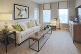 This single-floor residence offers a thoughtfully arranged layout with a cohesive neutral palette throughout. The living room serves as the central gathering space, featuring plush carpeting, a ceiling fan, and direct access to an outdoor area through a glass-paned door, complemented by a side window that invites natural light and views of surrounding greenery.

Adjacent to the living room, a defined dining area accommodates an intimate round table and seating for four. Track lighting overhead and a decorative sunburst mirror accent the space, while an open sightline connects it to the entryway corridor.

The galley-style kitchen is outfitted with white cabinetry, granite-look countertops, a tile backsplash, and wood-look flooring. It connects directly to a dedicated in-unit laundry area, adding everyday convenience.

Two bedrooms each feature carpeting, ceiling fans, and windows with garden views. Both rooms offer closet space, with one including a walk-in closet with built-in shelving. The shared full bathroom includes a tiled shower-tub combination, wood-look flooring, a white vanity, and granite-look countertops, completing this practical and comfortably designed residence.