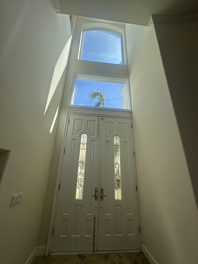 Gran entrada de doble puerta con paneles de vidrio decorativos, ventanas altas y detalle de travesaño. - 8120 Billowvista Dr