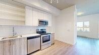 Located at 7288 Maple Street in Mission, BC, this efficiently designed single-floor unit offers a clean, modern aesthetic with thoughtful use of space. The open-concept kitchen and living area serves as the heart of the unit, featuring a full suite of stainless steel appliances — including a refrigerator, electric range, built-in microwave, and dishwasher — paired with sleek white upper cabinetry, warm wood-toned lower cabinets, and a classic white subway tile backsplash. Light-toned laminate flooring flows seamlessly throughout the entire unit, contributing to a bright and cohesive feel. The living space connects naturally to a separate sleeping area, which benefits from a sliding closet and a large window that invites natural light. The full bathroom is finished in a crisp, all-white palette, showcasing large-format vertical wall tiles in the soaker tub and shower surround, wood-look tile flooring, a white vanity with brushed hardware, and quartz countertop. Clean white walls and recessed lighting throughout reinforce the unit's modern, move-in-ready character, making it a functional and stylish space in the heart of Mission.