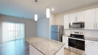 Located at 101 NW Mock Ave in Blue Springs, MO, this single-floor, one-bedroom, one-bathroom home offers a thoughtfully designed layout with a variety of functional spaces including a den, hallway, laundry room, and two closets. The open-concept kitchen is a standout feature, showcasing crisp white shaker cabinets, granite countertops, a central island with pendant lighting overhead, and a full suite of stainless steel appliances including a refrigerator, range, microwave, and dishwasher. Light wood-tone flooring runs throughout the main living areas, lending a clean and contemporary feel. The living room receives natural light through a large window, enhancing the bright, airy atmosphere of the space. The bedroom is generously proportioned with soft carpeting, a ceiling fan, and direct access to a walk-in closet outfitted with wire shelving for ample storage. A second closet provides additional organization options. The bathroom features a full soaking tub with tiled surround in a neutral wood-look finish. A dedicated laundry area and a flexible den space round out the practical offerings of this well-appointed home.