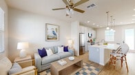 Located at 1901 N Williamson Blvd in Daytona Beach, FL, this thoughtfully designed one-bedroom, two-bathroom home offers a bright and airy coastal aesthetic across a single floor. Light wood-look flooring flows throughout, complementing the neutral white and soft gray palette that defines each room.

The kitchen serves as a functional centerpiece, featuring gray shaker-style cabinetry, a large island with a built-in sink and pendant lighting overhead, stainless steel appliances, and ample counter space — ideal for both everyday cooking and casual dining. A dedicated dining area adjacent to the kitchen provides additional space for meals and gatherings.

The living room is welcoming and well-lit, with natural light pouring in through slatted blinds and a glass-paneled front door that opens to views of the surrounding neighborhood. A ceiling fan adds comfort, and the coastal-inspired décor creates a relaxed, inviting ambiance.

The bedroom is comfortably sized, featuring windows that bring in natural light, a ceiling fan, and a wall-mounted TV. The closet provides organized storage, and both bathrooms are clean and modern, with one featuring a walk-in shower with full tile surround.

The exterior includes a green yard area visible from the dollhouse view, rounding out this well-appointed Daytona Beach home.