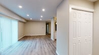 This well-appointed single-floor residence offers a clean, modern aesthetic with a thoughtfully designed open-concept layout. Warm neutral tones and wood-look laminate flooring run throughout, creating a cohesive and inviting atmosphere across all living areas.

The main living area is bright and open, illuminated by recessed lighting and a sliding glass door dressed with vertical blinds that allows natural light to flow in. The space is generously proportioned, offering flexibility for various furniture arrangements.

The kitchen is a standout feature, showcasing granite countertops, crisp white cabinetry, and a full suite of stainless steel appliances including a refrigerator, electric range, microwave, and dishwasher. A peninsula with an integrated sink and stylish pendant lighting above provides both additional prep space and a casual dining option. Accent storage panels in a muted blue-grey finish add a designer touch.

The bedrooms are comfortably sized with neutral walls, wood-look flooring, and ceiling fans with light fixtures. Windows with blinds allow for controlled natural light and privacy.

The bathroom is finished with a white vanity, matte black hardware accents including towel bars and a ring holder, a wall mirror, and matching wood-look flooring, lending a modern and cohesive feel. The overall design is clean, functional, and move-in ready.