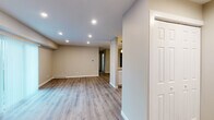 This well-appointed single-floor residence offers a clean, modern aesthetic with a thoughtfully designed open-concept layout. Warm neutral tones and wood-look laminate flooring run throughout, creating a cohesive and inviting atmosphere across all living areas.

The main living area is bright and open, illuminated by recessed lighting and a sliding glass door dressed with vertical blinds that allows natural light to flow in. The space is generously proportioned, offering flexibility for various furniture arrangements.

The kitchen is a standout feature, showcasing granite countertops, crisp white cabinetry, and a full suite of stainless steel appliances including a refrigerator, electric range, microwave, and dishwasher. A peninsula with an integrated sink and stylish pendant lighting above provides both additional prep space and a casual dining option. Accent storage panels in a muted blue-grey finish add a designer touch.

The bedrooms are comfortably sized with neutral walls, wood-look flooring, and ceiling fans with light fixtures. Windows with blinds allow for controlled natural light and privacy.

The bathroom is finished with a white vanity, matte black hardware accents including towel bars and a ring holder, a wall mirror, and matching wood-look flooring, lending a modern and cohesive feel. The overall design is clean, functional, and move-in ready.