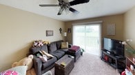 This single-floor residence offers a thoughtfully designed layout across several distinct living spaces. The kitchen serves as a functional centerpiece, showcasing rich dark espresso cabinetry paired with a decorative tile backsplash, stainless steel appliances including a built-in microwave and range, and warm hardwood-style flooring. A central island with a light-toned countertop provides additional prep space and casual seating, while pendant lighting adds a polished finishing touch. Ample upper and lower cabinet storage makes this kitchen as practical as it is visually appealing.

The living room features carpet flooring, a ceiling fan with integrated lighting, and a sliding glass door that opens to an outdoor area, inviting natural light and views of the surrounding greenery. The bedroom accommodates a comfortable layout with carpeted floors, a textured ceiling, and access to a walk-in closet with organized shelving and hanging space. A second bedroom provides similar comfort with carpeted flooring and a window with room-darkening drapes.

The bathroom is finished with tile flooring, a dark-framed vanity mirror with overhead lighting, a single-sink vanity with storage, and a patterned shower curtain that adds a decorative element. Overall, the space presents a warm, lived-in atmosphere with cohesive design choices throughout.