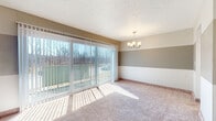 Located at 11150 Somerset Dr in North Royalton, Ohio, this single-floor home offers a well-organized layout with a variety of thoughtfully appointed spaces throughout. The living and dining area is a standout feature, highlighted by large sliding glass doors dressed with vertical blinds that flood the room with natural light and provide views of the surrounding wooded landscape. A classic chandelier adds an elegant touch to the dining space, which is finished with warm, neutral-toned carpeting and two-tone painted walls. The galley-style kitchen is well-equipped, featuring rich dark wood cabinetry, granite countertops, tile flooring, stainless steel appliances including a refrigerator and range, and a stainless sink — all opening toward the bright living area. The bedrooms are spacious and carpeted, each with windows fitted with vertical blinds that bring in natural light. The bathrooms have been tastefully updated; one features a tiled tub-and-shower combination with decorative mosaic accents, a dark wood vanity, and granite countertop, while the second includes a glass-door walk-in shower with similar tile finishes, a granite vanity, and tile flooring. Textured ceilings are consistent throughout the home, contributing to its classic residential character.