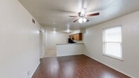 Located at 2512 W Hickory St in Denton, TX, this 2-bedroom, 1-bathroom unit offers a practical and well-organized single-floor layout. The combined kitchen and living area forms the heart of the home, with the living space featuring warm wood-look laminate flooring, a ceiling fan with light fixture, and a window that brings in natural light. The adjacent kitchen is equipped with honey-toned wood cabinetry, granite-look countertops, tile flooring, and a full suite of stainless steel appliances including a refrigerator, range, and microwave. Both bedrooms continue the wood-look flooring theme and are outfitted with ceiling fans and windows that allow natural light to filter in. The primary bedroom offers a comfortable footprint, while the secondary bedroom includes a closet with bifold doors. A hallway connects the bedrooms to the shared full bathroom, which features a tub-shower combination with floor-to-ceiling tile surround and chrome fixtures. Additional utility space with tile flooring provides functional versatility. Neutral wall tones and consistent finishes throughout give the unit a clean, cohesive feel.