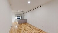 Located at 230 Goldsboro St S in Wilson, NC, this one-bedroom, one-bathroom loft blends industrial character with modern finishes throughout its well-appointed single floor. The open-concept living and kitchen area features warm hardwood floors, crisp white walls, and recessed and track lighting overhead, creating a bright and functional space. The kitchen is equipped with stainless steel appliances, including a microwave, range, and refrigerator, complemented by gray cabinetry and an island with a peninsula countertop — ideal for both cooking and casual dining. The generously sized bedroom showcases soaring ceilings, exposed brick walls, a rustic wooden structural column, and a large window that invites natural light and outdoor views. Industrial-style exposed conduit adds to the loft's character. A dedicated closet features built-in wire shelving for ample storage. The bathroom offers a clean, classic aesthetic with penny tile flooring, a full tub-shower combination, a vanity, and chrome fixtures. A staircase is also part of the layout, adding to the vertical dimension of this distinctive urban residence.